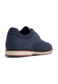 Zapatos azul marino con parte superior de cuero liso y malla, puntera redonda, diseño con cordones, suela blanca contrastante y acentos texturizados.