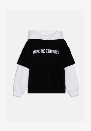 Haine de tip oversized, alb-negru, cu un design în două straturi. Partea din față are inscripția "MOSCHINO COUTURE" în text alb.