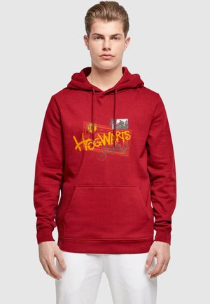 Rød hættetrøje med en frontlomme, prydet med Hogwarts-grafik i gul og et fotoaccent. Fremstillet af blødt materiale med snoretræk i hætten.
