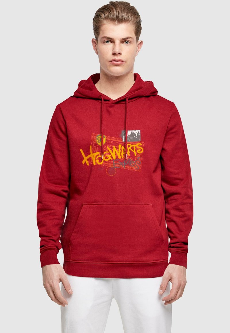 Röd hoodie med en framficka, med Hogwarts-grafik i gult och ett fotoaccent. Tillverkad av mjukt tyg med en dragsko-hood.