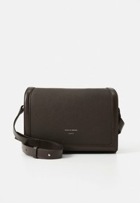 Brązowa skórzana torba na ramię z fakturowaną powierzchnią, prostokątnym kształtem, klapą zamykającą i regulowanym paskiem. Na przodzie znajduje się logo marki.