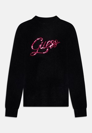 Pull noir à manches longues avec poignets et col côtelés, arborant un logo "Guess" en sequins roses brillants sur la poitrine.
