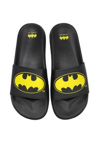 Chanclas negras con una superficie texturizada y una correa ancha que presenta el logo amarillo de Batman. Diseño simple adecuado para el uso casual.