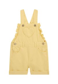Peto de mezclilla amarillo con tirantes con volantes, un parche en forma de corazón, dos bolsillos frontales y pantalones cortos con dobladillo.