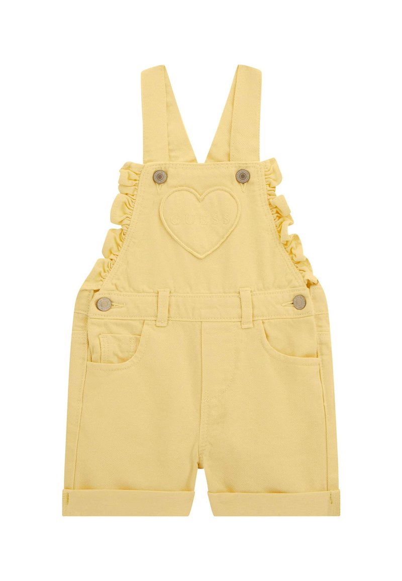 Peto de mezclilla amarillo con tirantes con volantes, un parche en forma de corazón, dos bolsillos frontales y pantalones cortos con dobladillo.