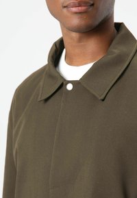 Olijfgroene colbertjas met een knoopsluiting, voorzien van een gladde textuur en een klassiek ontwerp, gezien vanaf de bovenrug en halslijn.