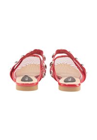 Sandalias rojas con un diseño de malla, acentos plateados, tira trasera y suela plana en tono beige. Presentan una plantilla suave con un detalle de logo.