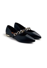 Black flat shoes with a pointed toe, featuring a gold circular accent design across the instep and a metallic gold heel detail.