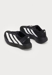 Scarpe da corsa Adidas nere con tre strisce bianche sui lati e suole spesse imbottite, viste da un angolo posteriore laterale.