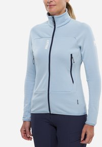 Helle blaue Fleecejacke mit hohem Kragen, ausgestattet mit einem strukturierten Muster, navyfarbener Reißverschluss und zwei seitlichen Reißverschlusstaschen.