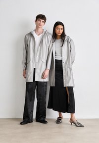 Imperméables gris clair avec capuche, présentant des fermetures à pression et des poches avant. Pantalons en satin noir et une jupe noire avec une fente sur le côté.