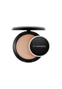 Cipria compatta rotonda in una custodia nera opaca, con una superficie liscia di un beige chiaro e un puff applicatore bianco.