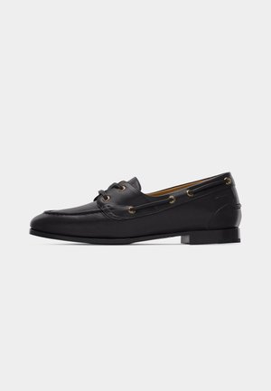 Black leather men's loafer with lace-up detail, low heel, and moc toe stitching, shown in side profile on a white background.