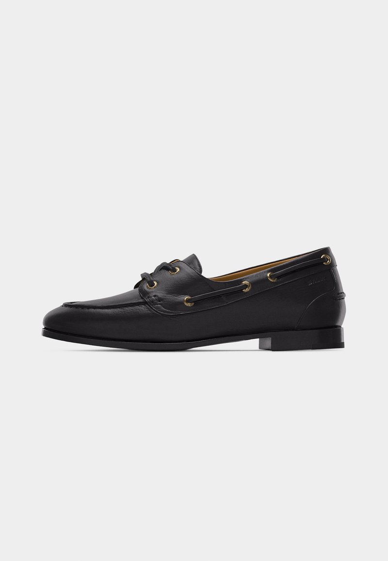 Mocassin pour homme en cuir noir avec détails à lacets, talon bas et coutures moc toe, montré en profil latéral sur fond blanc.