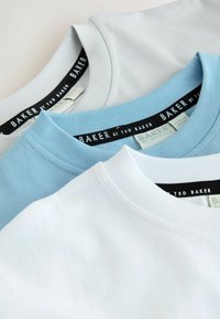 Drei T-Shirts mit Rundhalsausschnitt in Weiß, Hellblau und Grau. Hergestellt aus weichem Stoff mit sichtbaren Nähten und schwarzen Markenetiketten an den Ausschnitten.