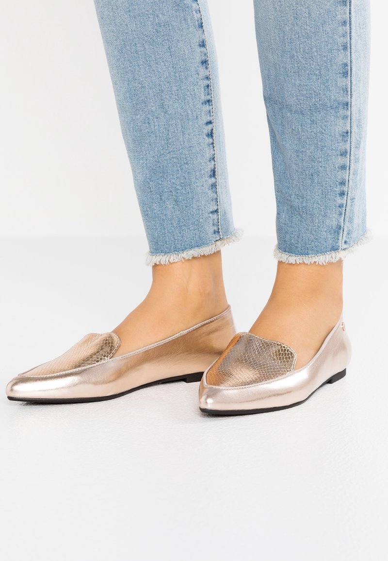 Ballerines slip-on rose métal avec un devant en imprimé serpent texturé. Fini lisse, petit talon, et une forme arrondie complètent le denim décontracté.