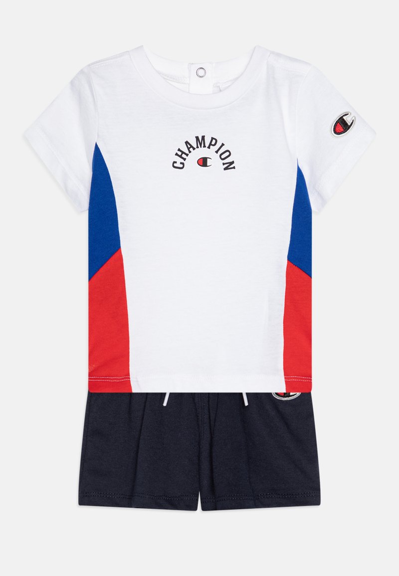 White cotton t-shirt with red and blue side panels, "Champion" logo above, short sleeves, paired with navy cotton shorts with drawstring.