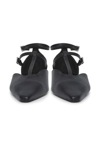 Zapatos planos de punta negra con correas en el tobillo y cierres de hebilla, mostrados desde el frente sobre un fondo blanco.