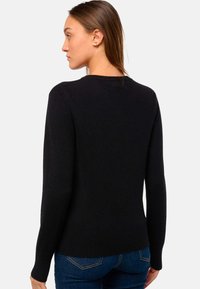 Pull noir à manches longues et col rond, fabriqué à partir d'un matériau doux et texturé. Poignets et ourlet côtelés, design ajusté.