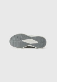 Dessous d'une chaussure Skechers grise avec une semelle texturée arborant un motif géométrique et un accent logo central en blanc.