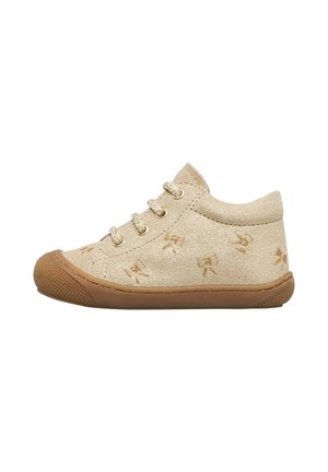 Beige småbørns sko med guldbroderi af sløjfe, guldøjer, tekstureret brun gummisål og rund tå, vist fra siden.