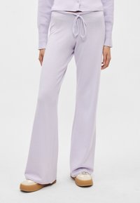 Μωβ παντελόνι φόρμας με καμπάνα από απαλό ύφασμα και ελαστική μέση με κορδόνι. Συνδυασμένο με μπεζ αθλητικά παπούτσια. Λείο υλικό και χαλαρή εφαρμογή.