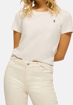 Licht beige katoenen T-shirt met korte mouwen, ronde hals en klein blauw logo op de linkerkant van de borst. Gecombineerd met crèmekleurige jeans.