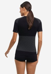 Czarny sportowy top z krótkimi rękawami, z teksturowanymi paskami na ramionach, bezszwowy i dopasowany. W komplecie czarne szorty.