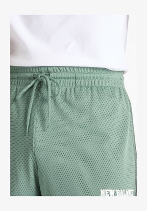 Lys grønne netshorts med elastisk talje og snore. Har små perforeringer for pusteevne og hvidt logo-detalje.