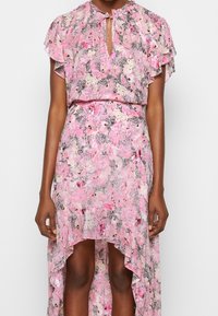 Vestido floral rosa con diseño de volantes, mangas cortas y escote en forma de ojo de cerradura. Presenta un dobladillo asimétrico y patrones intrincados en negro y tonos pasteles.