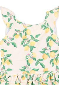 Żółty strój kąpielowy w wzór cytryn z falbaną na dole, kwiatowymi akcentami i zielonymi liśćmi na jasnobeżowym tle. Miękki, lekki materiał.