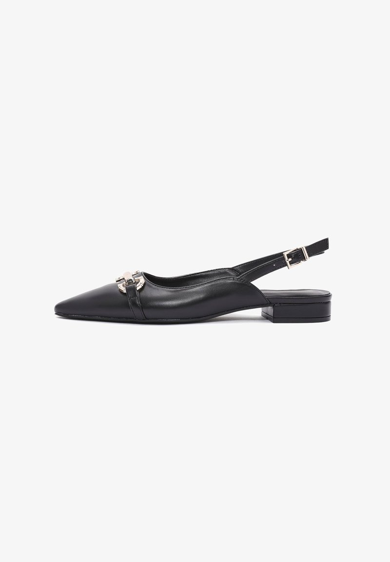 Chaussure slingback en cuir noir avec un bout pointu, un talon plat et une boucle décorative en argent à l'avant. Texture lisse, design minimaliste.