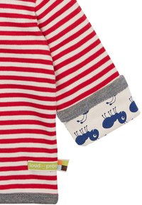 Manica a strisce rosse e bianche con polsino grigio, decorata con motivi di formiche blu. Include un'etichetta verde "loud + proud". Materiale in cotone.