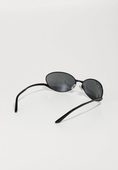 Ochelari de soare ovali negri cu lentile întunecate, ramă metalică elegantă, brațe subțiri și tampoane nazale transparente. Design minimalist pe un fundal alb.