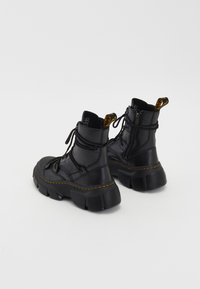 Black leather ankle boots with a chunky sole, lace-up front, side zipper, and yellow stitching detail. Textured finish with prominent hardware.