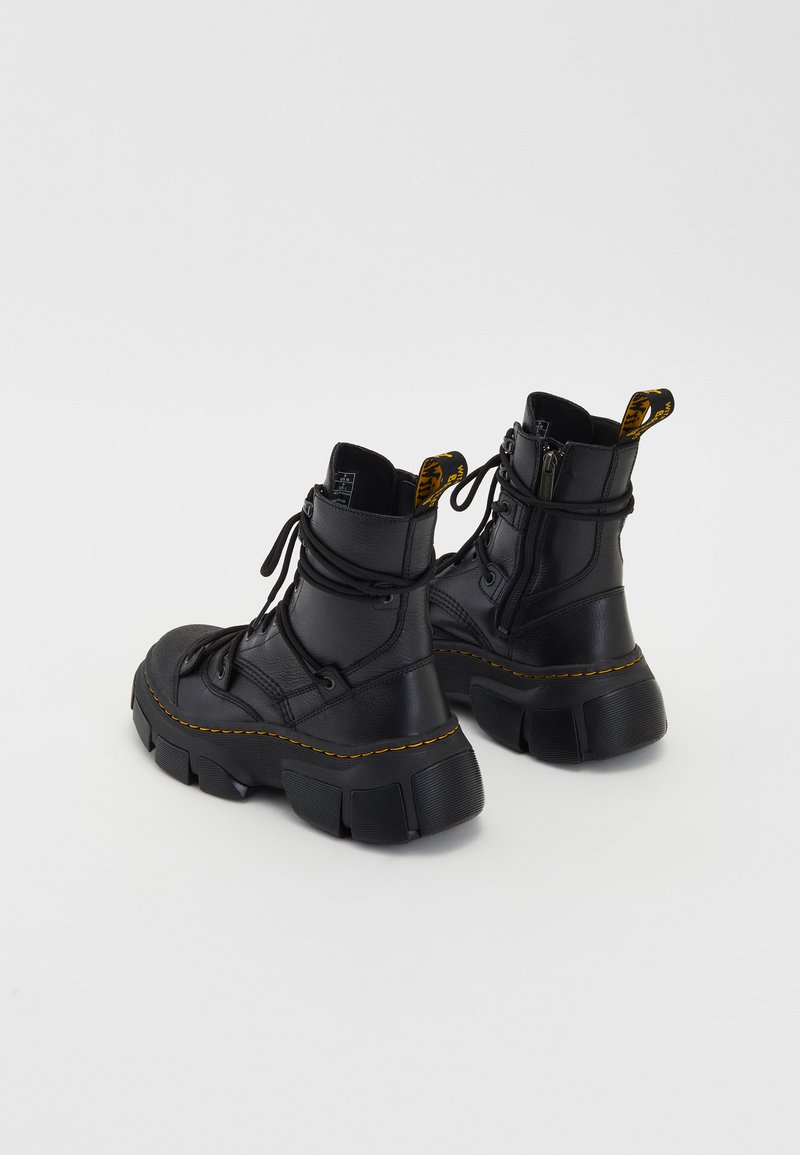 Bottines en cuir noir avec une semelle épaisse, un laçage à l'avant, une fermeture éclair sur le côté et des détails en couture jaune. Fini texturé avec un matériel saillant.