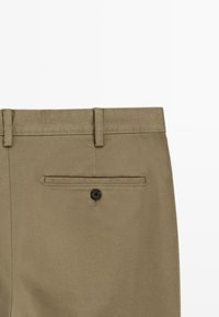 Khakihosen aus strukturiertem Stoff mit einer Gesäßtasche, die mit einem schwarzen Knopf gesichert ist, und Gürtelschlaufen entlang der Taille.