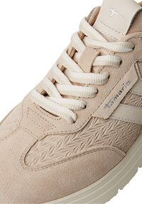 Baskets en daim beige avec un design texturé, lacets crème et une semelle en caoutchouc de couleur claire. Accent latéral notable en matériau clair.