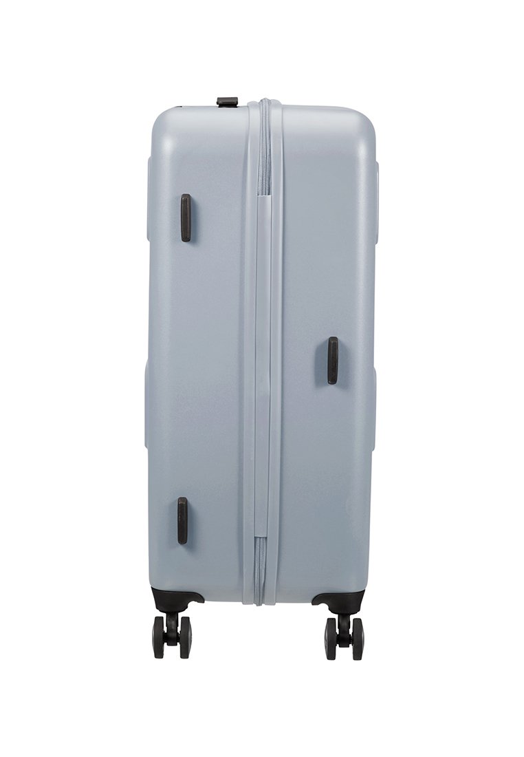 Maleta rígida de color azul claro, con una textura suave, cremalleras dobles y ruedas y acentos en negro. Diseño delgado y rectangular.