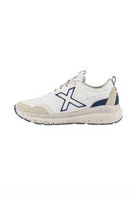 Zapatilla deportiva blanca con acentos en azul marino, parte superior de malla texturizada, puntas de ante y suela de goma salpicada. Presenta un prominente logotipo de "X".