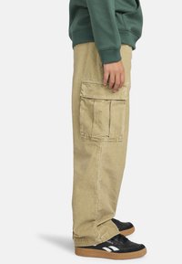 Beige Cargo-Hosen aus Baumwolle mit einem lässigen Schnitt, ausgestattet mit Seitentaschen, sichtbaren Nähten und einem geraden Bein.