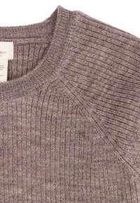 Nærbillede af en brun ribstrikket sweater, der viser rund halsudskæring og skuldersøm med synlig stofstruktur.