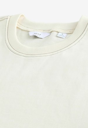 Crème kleurige sweatshirt met een ribbelrand en subtiele textuur. Labels geven merk en maat M aan. Regular fit ontwerp.