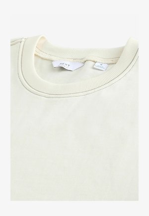 Sweatshirt de couleur crème avec un col côtelé et une texture subtile. Les étiquettes indiquent la marque et la taille M. Design à coupe régulière.