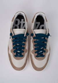 Sneaker con una toma in suede beige, dettagli in pelle bianca e lacci testurizzati color teal. Presenta un dettaglio perforato vicino alla punta e una soletta nera.