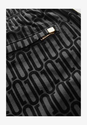 Fekete szövet, amelyen ismétlődő fényes minta található a "LOGO" felirattal. Tartalmaz egy arany fém cipzárt a záráshoz. Puha tapintású.