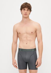 Σκούρο γκρι εσώρουχο boxer από απαλό ύφασμα, με λογότυπο στη μέση σε πράσινο χρώμα και αντί�θετες ραφές.