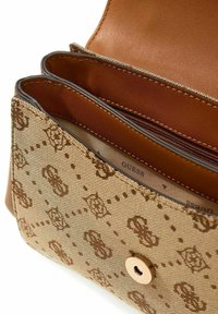 Sac à main marron et beige avec une surface texturée ornée d'un motif de logo, une fermeture à bouton-pression unique, et deux compartiments internes avec une fermeture éclair.