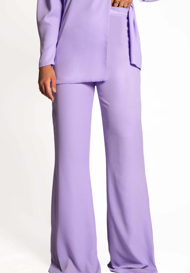 Conjunto de dos piezas en lila que presenta una blusa de mangas largas con un corte holgado y pantalones de pierna ancha, ambos confeccionados en una tela suave y ligera.