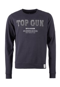 Marineblå sweatshirt med lange ærmer, rund hals og trykt tekst. Har "TOP GUN" i fed skrift og logoetikette i nederste kant. Blød stofstruktur.